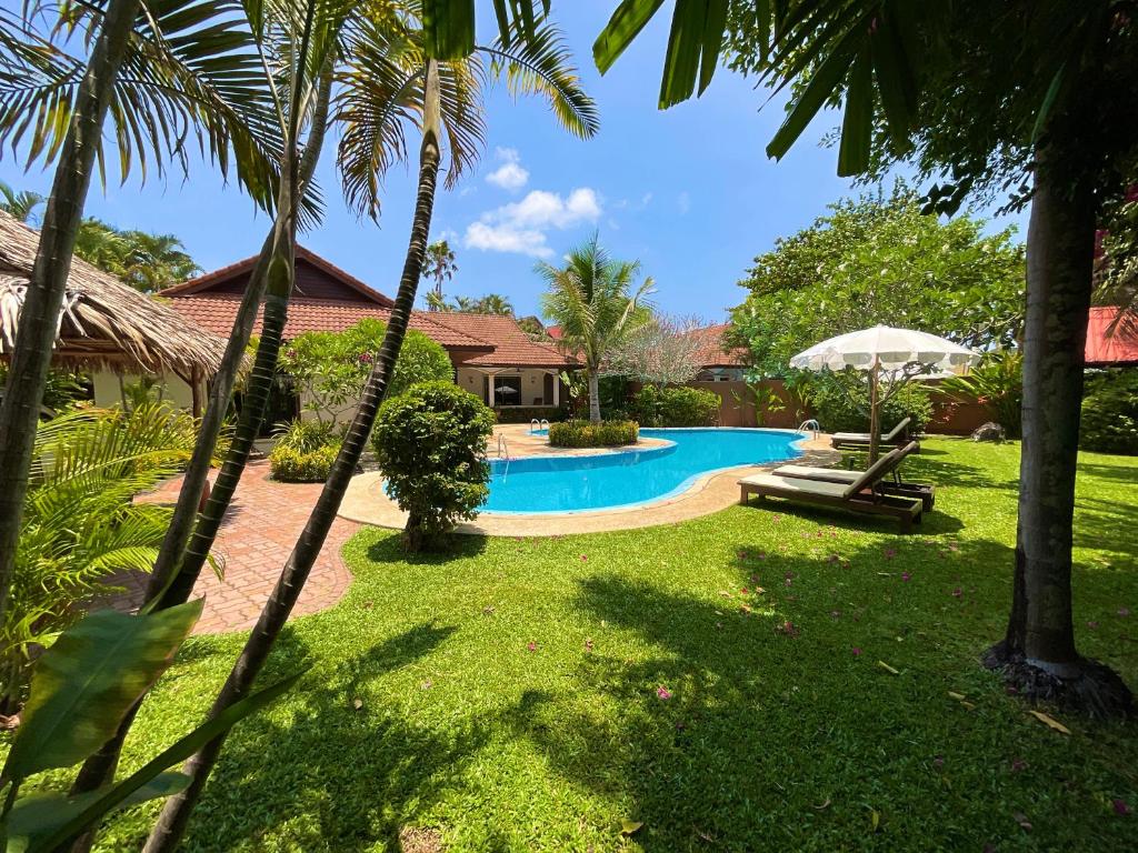 a swimming pool in a yard with palm trees at Coconut Paradise Holiday Villas in Rawai Beach