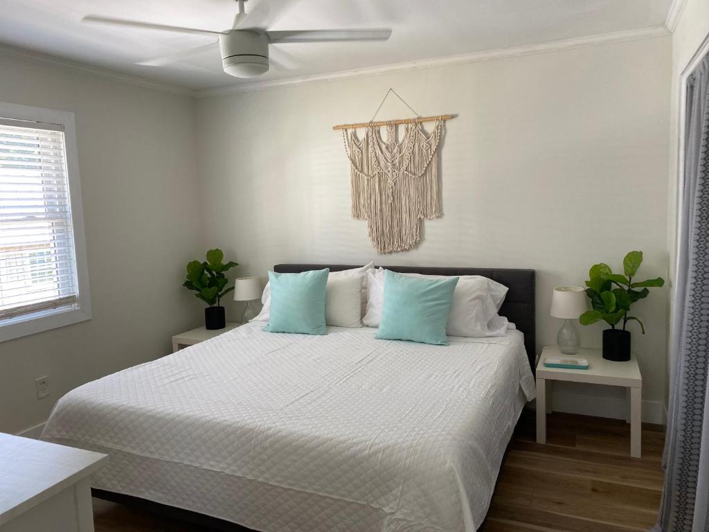 a white bedroom with a bed with blue pillows at Island Time in Carolina Beach