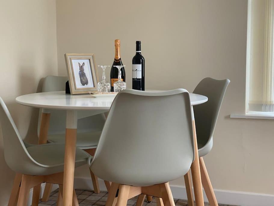 a table with four chairs and two bottles of wine at The Burrow, Langholm, Dumfries and Galloway in Langholm