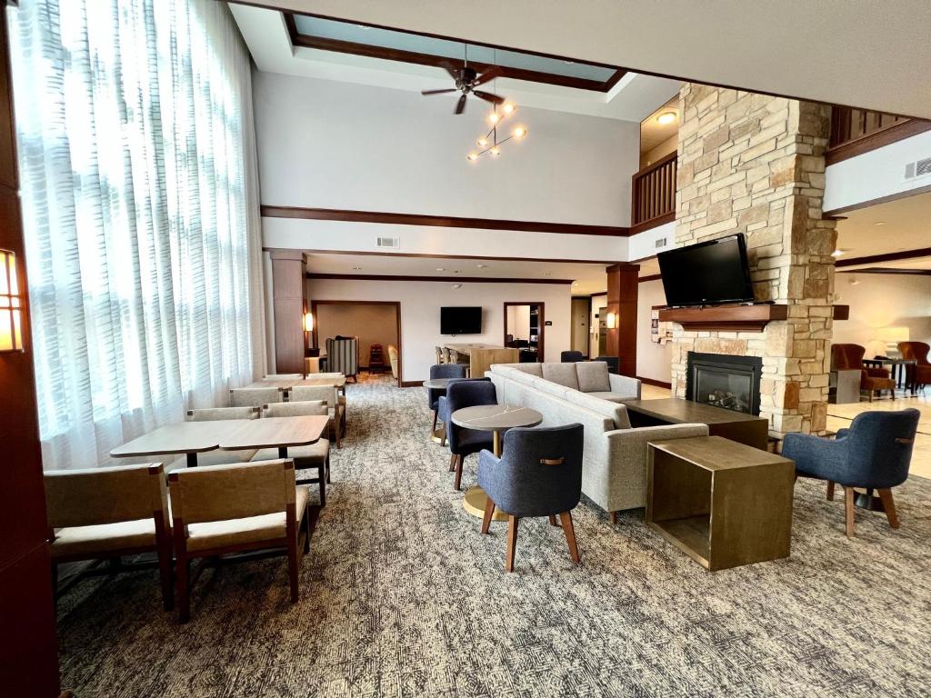 a lobby with tables and chairs and a fireplace at Staybridge Suites Milwaukee West-Oconomowoc, an IHG Hotel in Oconomowoc