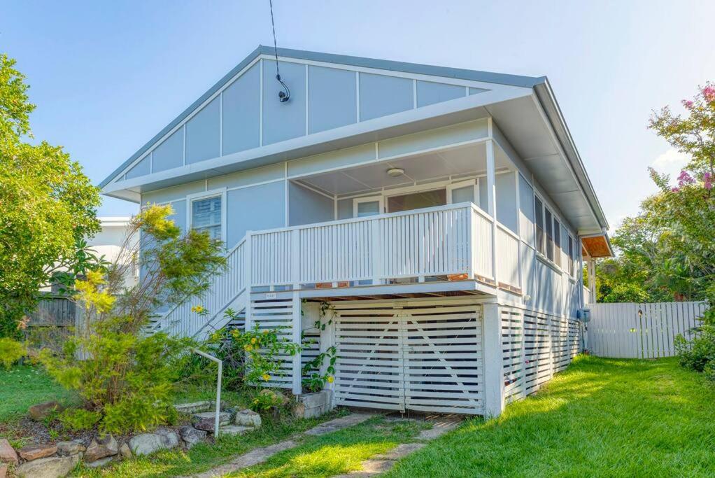 a house with a balcony and a yard at Stylish 1950s Moffat Beach House in Caloundra