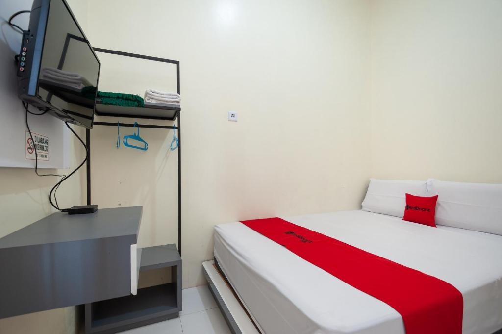 SolokにあるRedDoorz Syariah near RS Tentara Solokのベッド1台とテレビが備わる小さな客室です。