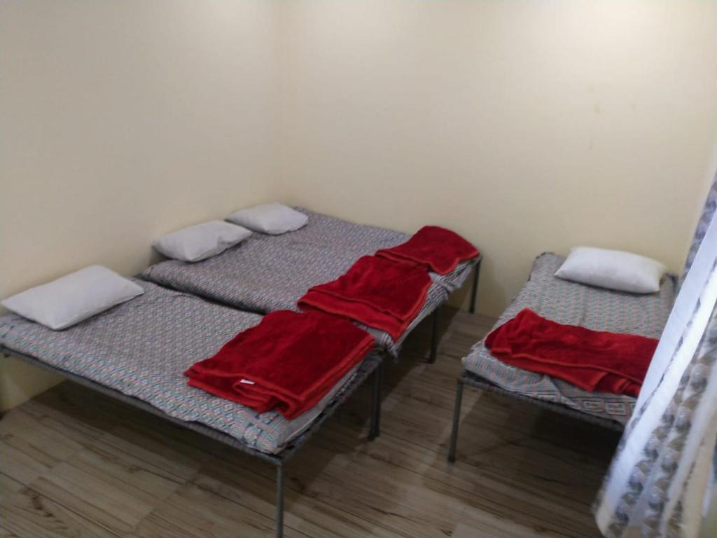 2 łóżka w pokoju z czerwonymi kocami w obiekcie Patel's Home w mieście Bhuj