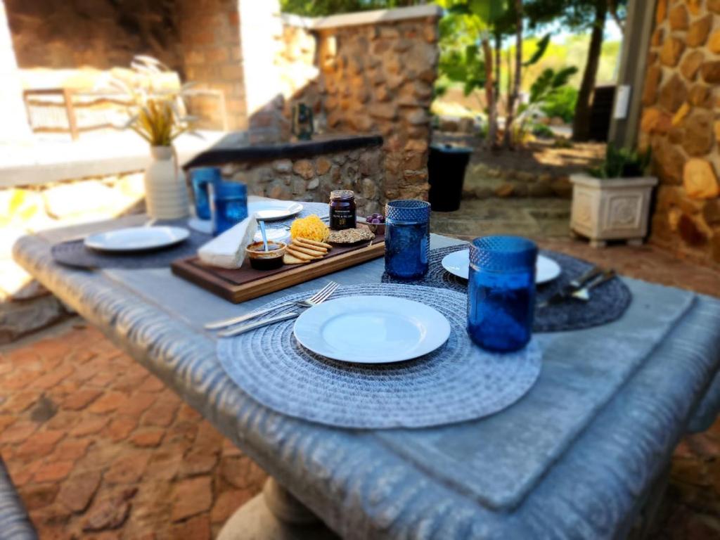 einem blauen Tisch mit Tellern und blauen Gläsern darauf in der Unterkunft Stone Cottage Riebeek Valley in Riebeek-Wes