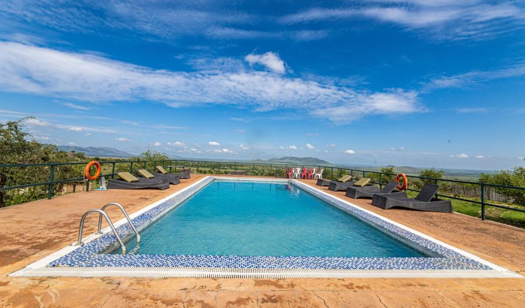 a swimming pool with chairs and a view of the ocean at Serengeti Safari Lodge in Banagi