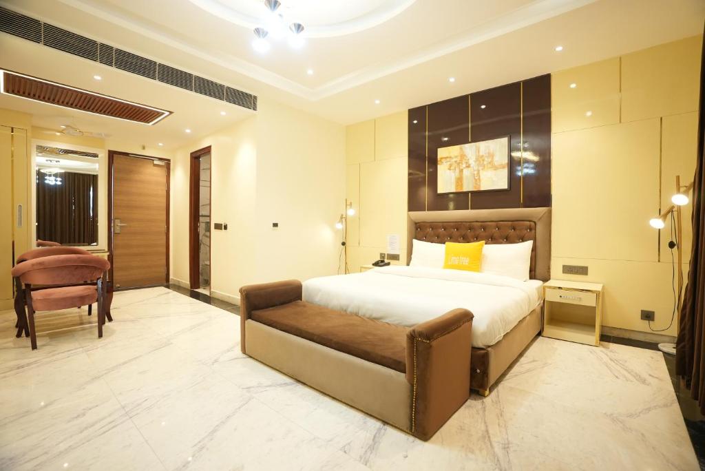 a bedroom with a large bed and a chair at Lime Tree Hotel and Banquet Greater Noida in Greater Noida