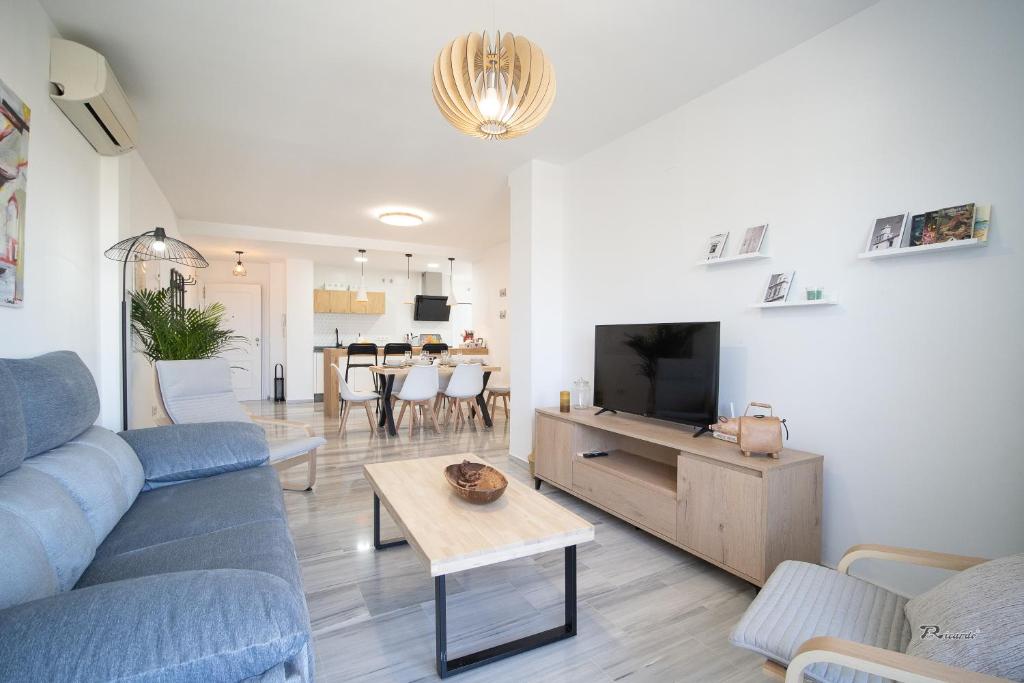 a living room with a blue couch and a tv at Balcón a Doñana in Sanlúcar de Barrameda