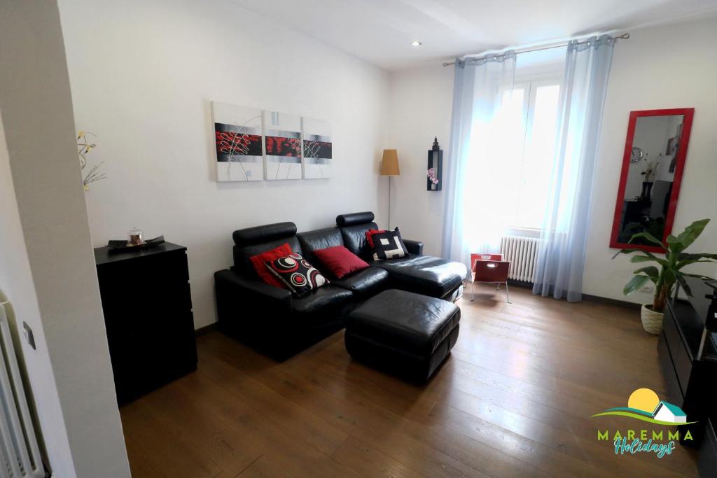 - un salon avec un canapé et une chaise dans l'établissement Maremma Holidays -Trento Apartment, à Follonica