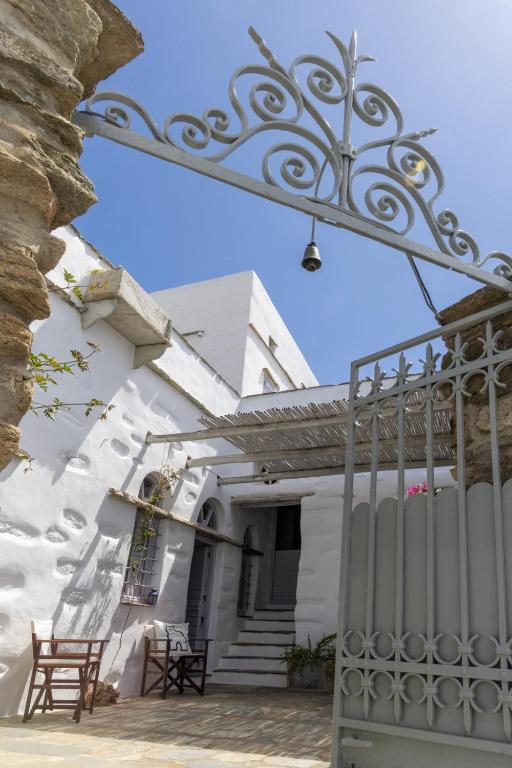 a white house with a gate and chairs at Traditional Tinos Olive Mill House in Khatzirádhos
