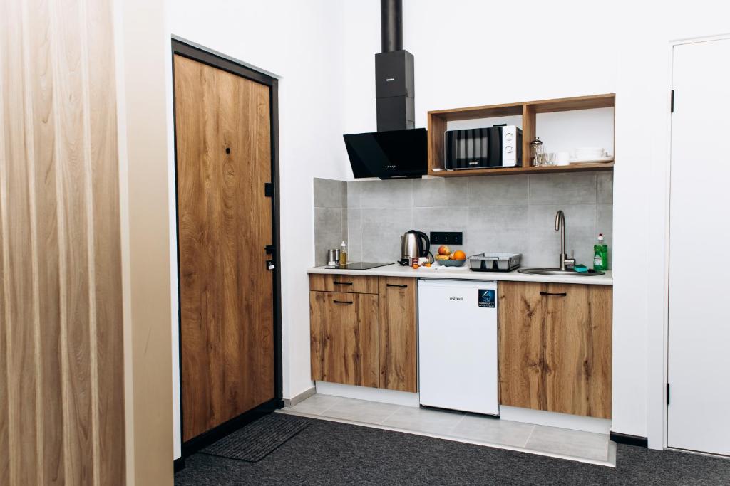 een keuken met houten kasten en een witte koelkast bij RESA apart - нові smart-квартири біля річки in Oezjhorod