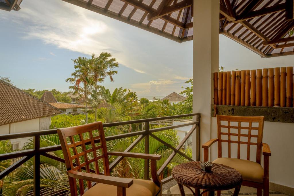 a balcony with two chairs and a view of trees at Ecosfera Hotel & Spa in Canggu