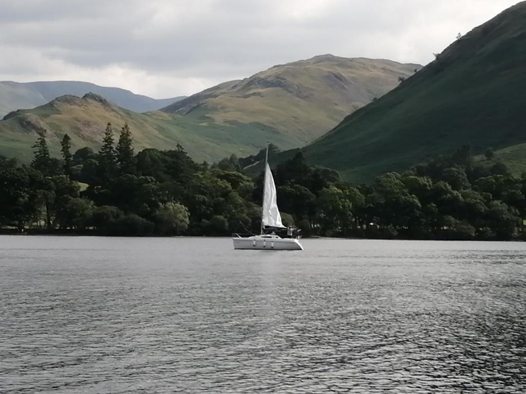 a sailboat on a lake with mountains in the background at Lakes and Eden Valley. Thornhill Cabin in Long Marton