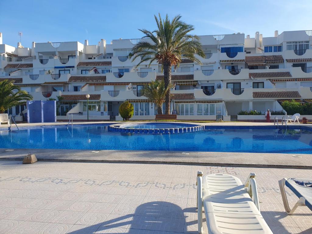 - une piscine avec 2 chaises longues devant un bâtiment dans l'établissement Puerto Tomas Maestre, à San Javier