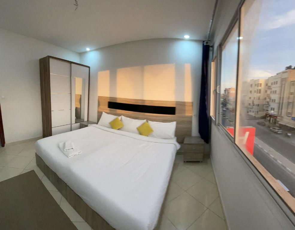 uma grande cama branca num quarto com uma janela em HOTEL NOON em Laayoune