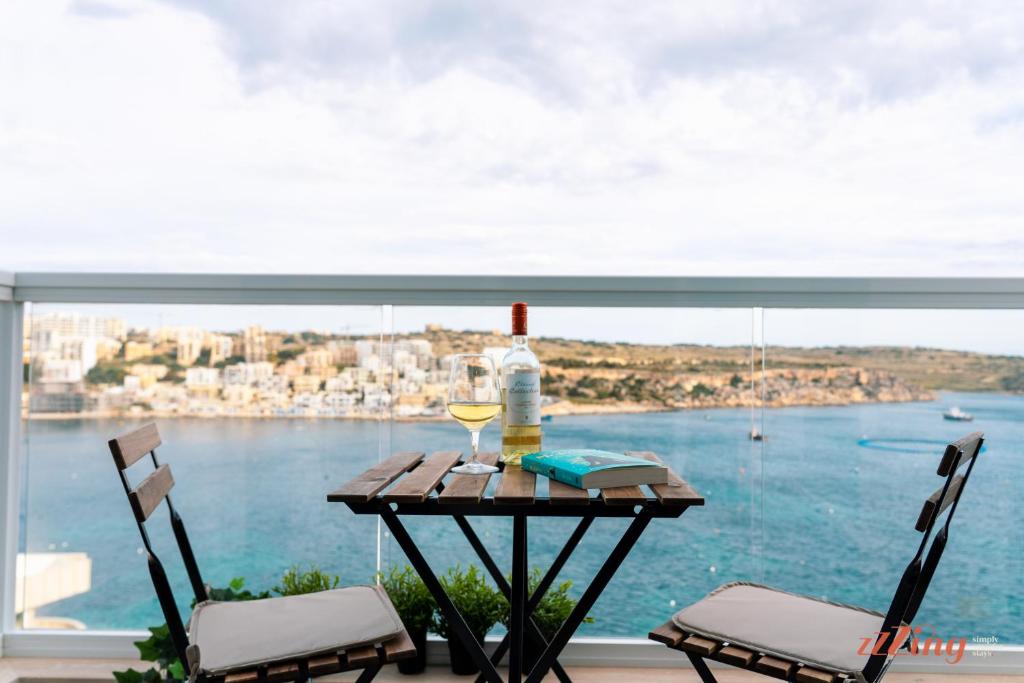 uma mesa com uma garrafa de vinho e um copo em Seashore Stays - Stunning apartments right by the sea em St. Paul's Bay