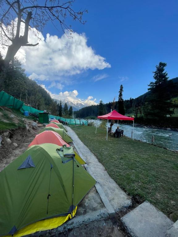 a group of tents parked next to a river at The woodswalk Treks and tours in Pahalgām