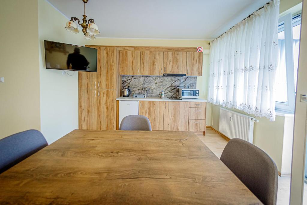 uma sala de jantar com uma grande mesa de madeira e cadeiras em Stara Piekarnia - Studio Dworcowa em Olsztyn
