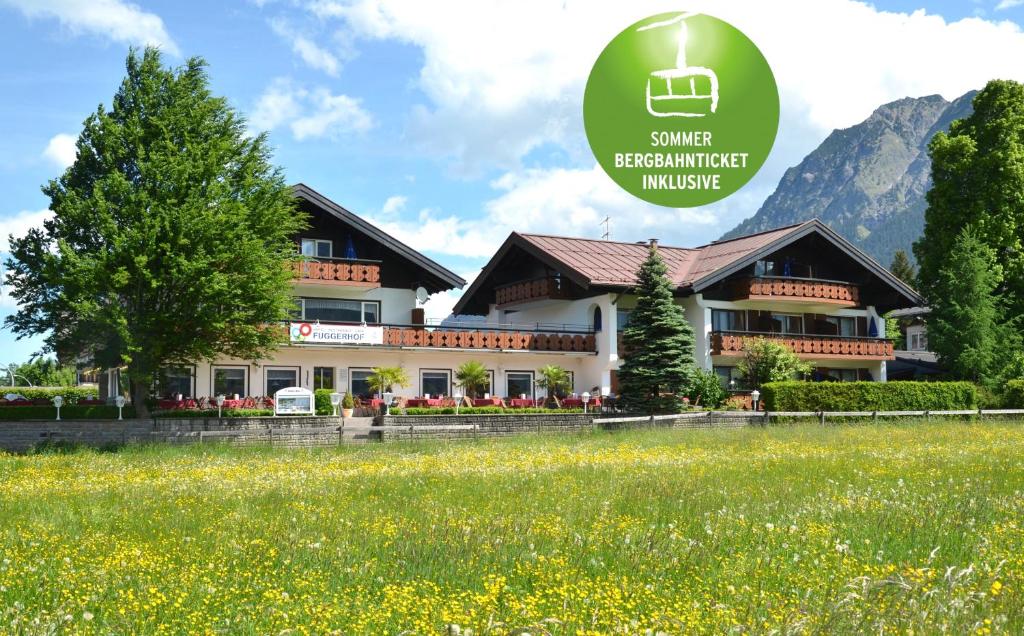 a building with a field in front of it at Hotel Cafe Fuggerhof in Oberstdorf