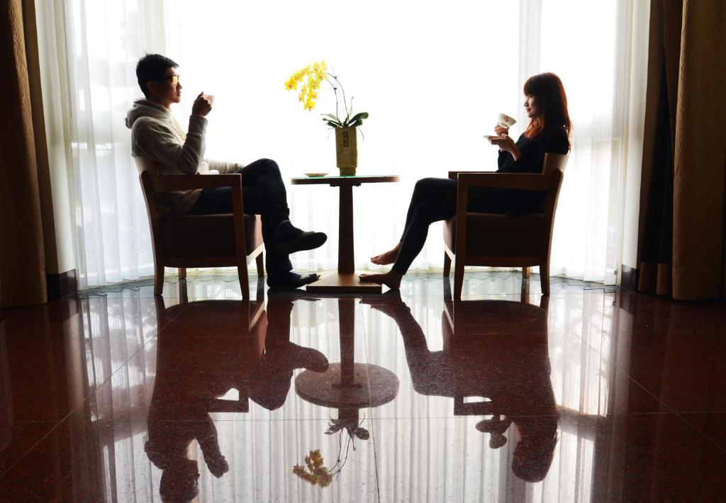 a man and woman sitting at a table in a room at Yunju House in Jiaoxi