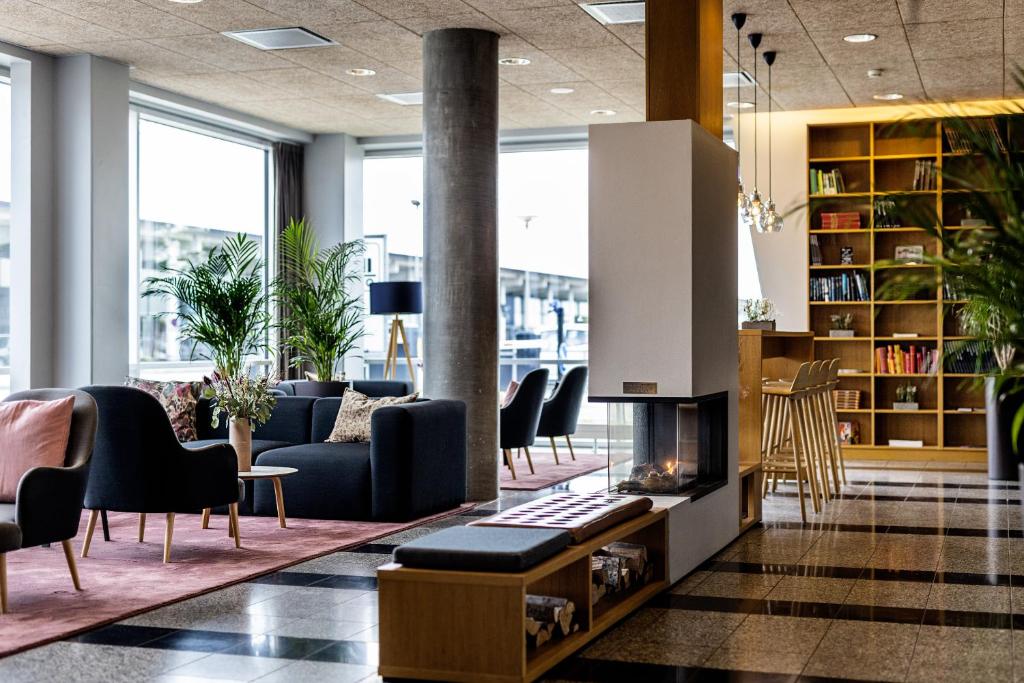 eine Lobby mit einem Sofa, Stühlen und einem Kamin in der Unterkunft Aalborg Airport Hotel in Aalborg