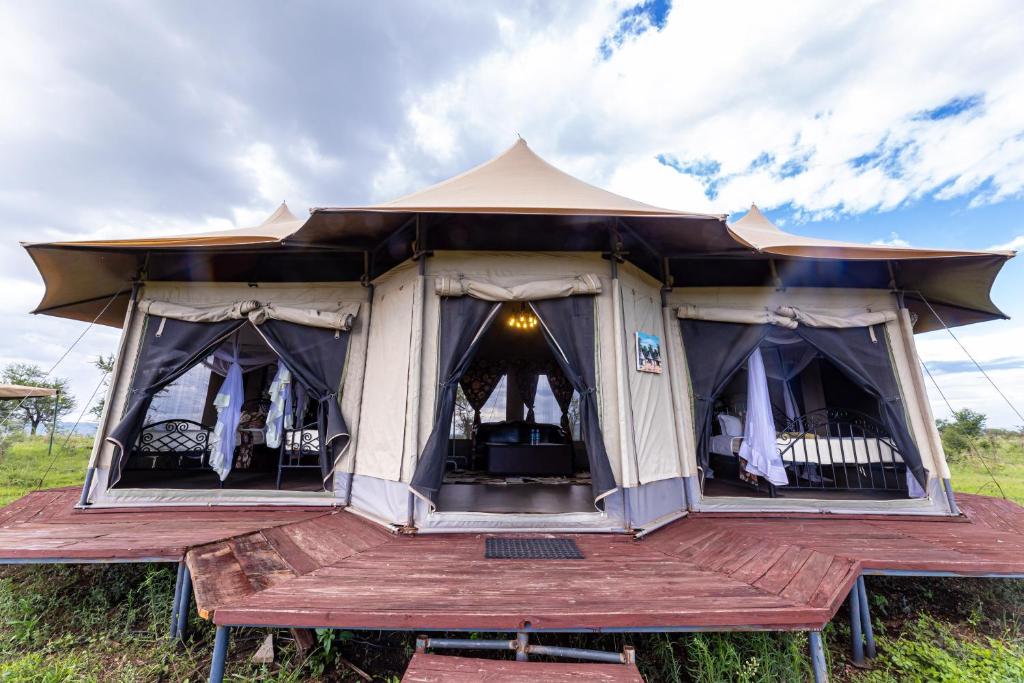a tent with a wooden deck in a field at Serengeti Wildebeest Camp in Banagi
