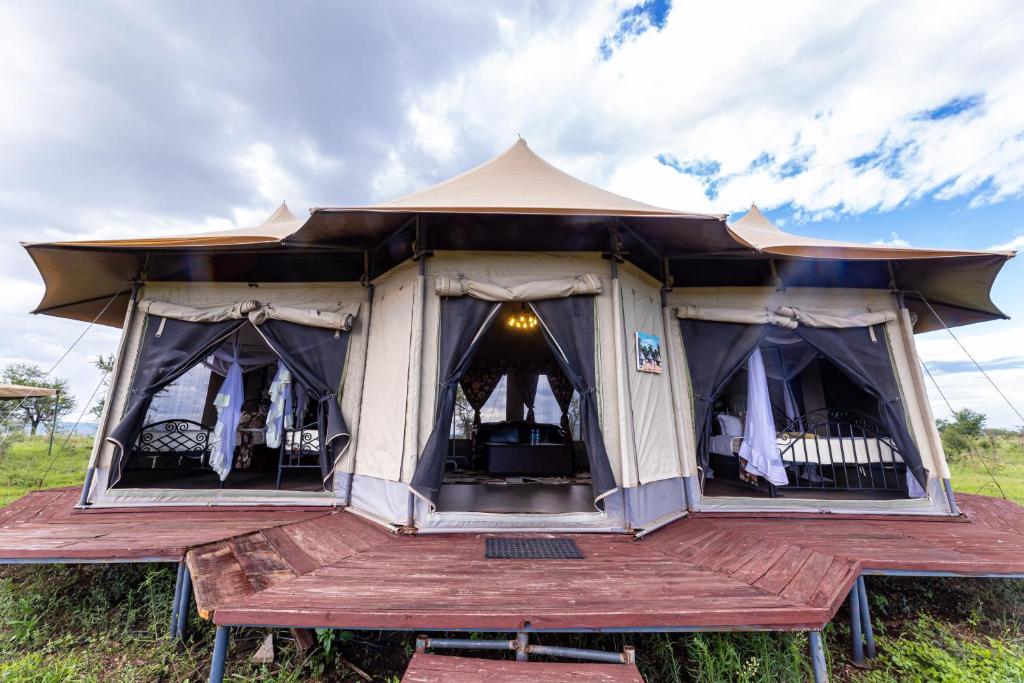 een tent met een houten terras in een veld bij Serengeti Wildebeest Camp in Banagi