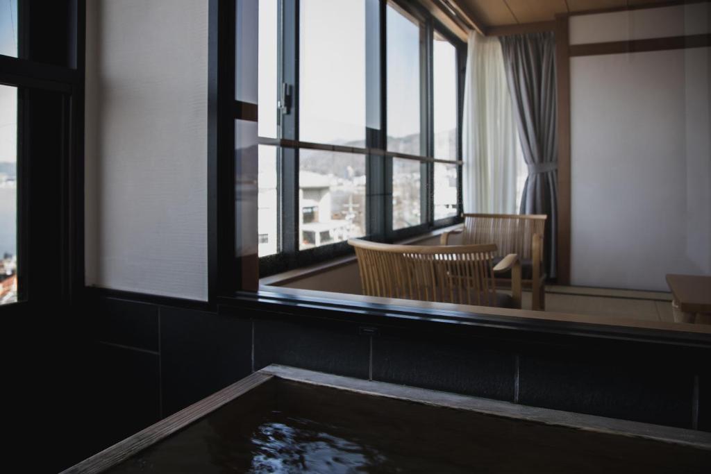 a bath tub in a room with windows at Sui Suwako in Suwa