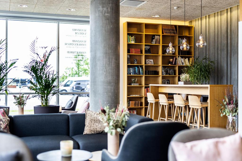 a library with couches and chairs and a book shelf at Aalborg Airport Hotel in Aalborg