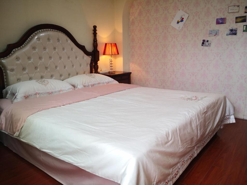 um quarto com uma grande cama branca e um candeeiro em 空中花园民宿 贵阳火车站店 em Guiyang