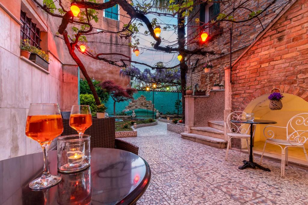Dois copos de vinho sentados numa mesa num pátio em Hotel Casa Boccassini em Veneza