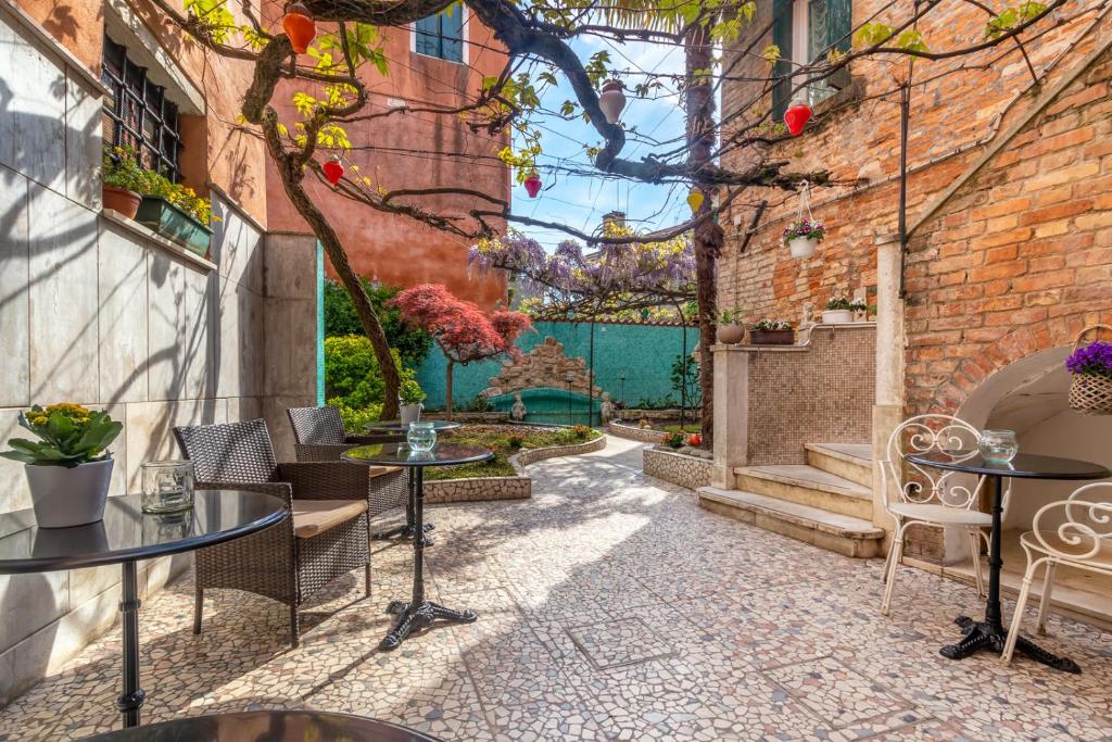 a courtyard with tables and chairs and a brick wall at Hotel Casa Boccassini in Venice