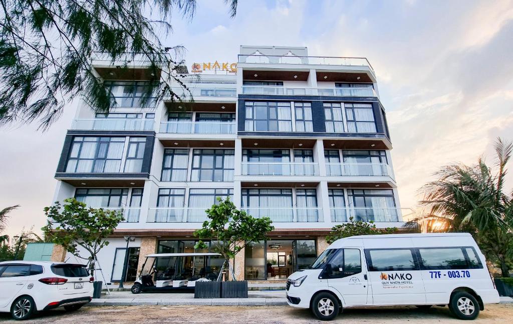 duas carrinhas brancas estacionadas em frente a um edifício em NAKO QUY NHON HOTEL em Quy Nhon