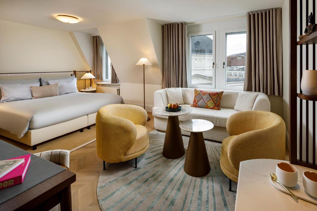 a hotel room with a bed and a couch and chairs at Small Luxury Hotel Ambassador Zurich in Zürich