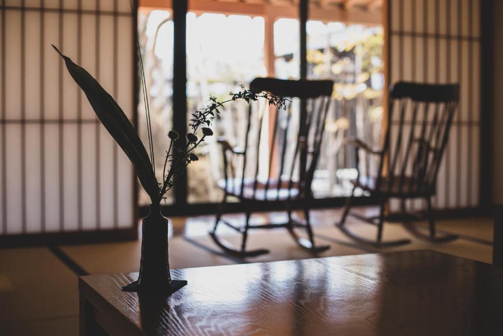 a vase with flowers on a table with two chairs at Sui Suwako in Suwa