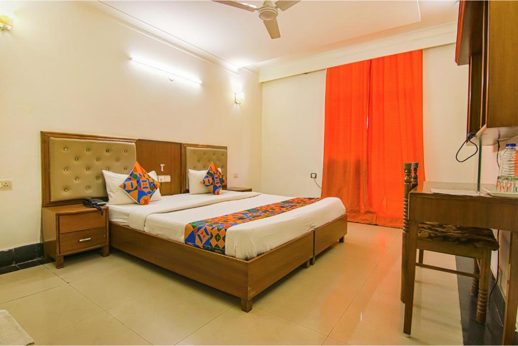 1 dormitorio con 1 cama grande y cortina roja en FabExpress JDM Residency, en Gurgaon