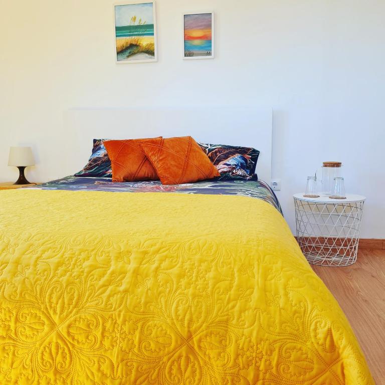 a yellow bed with two orange pillows on top of it at Quinta JR - Casa de campo in Carregal