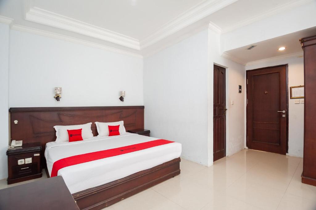 1 dormitorio con 1 cama grande con almohadas rojas en RedDoorz Syariah near RS Yos Sudarso Padang en Padang