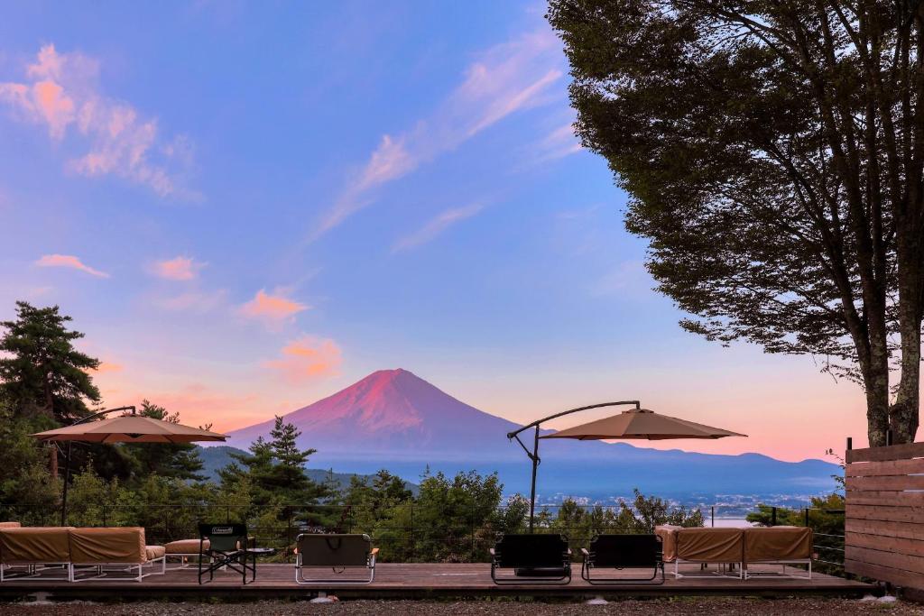 富士河口湖町にあるRetreat Camp Mahorobaの山の景色を望む客室で、椅子とパラソルが備わります。