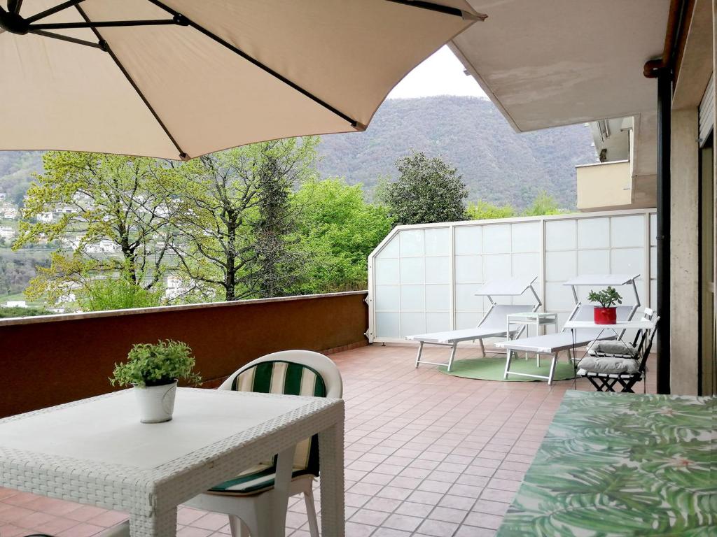 uma varanda com mesas e cadeiras e um guarda-sol em Casetta con terrazza em Como