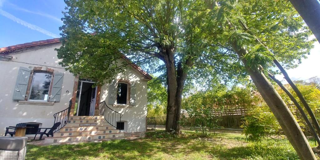 una casa blanca con un árbol en el patio en Villa Garona avec billard proche Pyrénées en Cazères