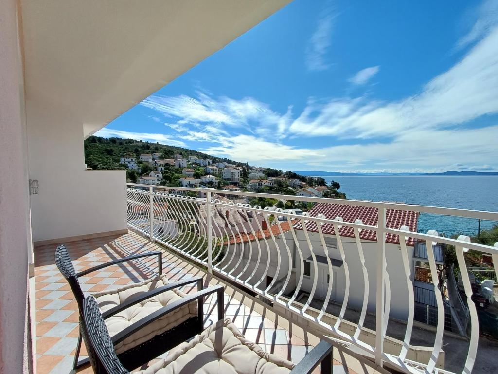 einen Balkon mit Stühlen und Blick auf das Wasser in der Unterkunft Apartments Jakšić in Trogir