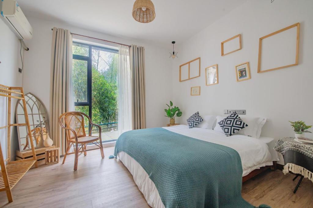 a white bedroom with a bed and a window at Yangshuo Jing Yuan Inn in Yangshuo