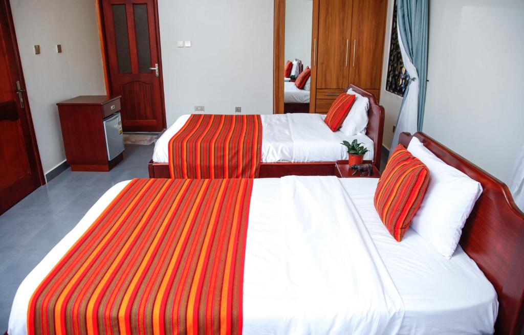 een hotelkamer met 2 bedden met rode en oranje gestreepte lakens bij Fred and Winnie BnB in Kampala