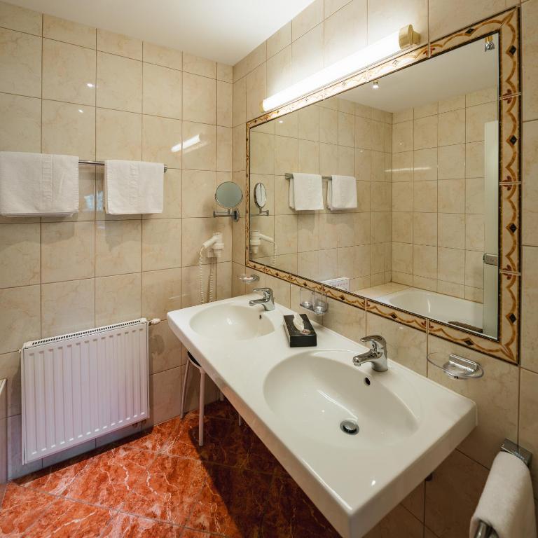 a bathroom with a sink and a mirror and a tub at Hotel Garni Alpenruh-Micheluzzi in Serfaus