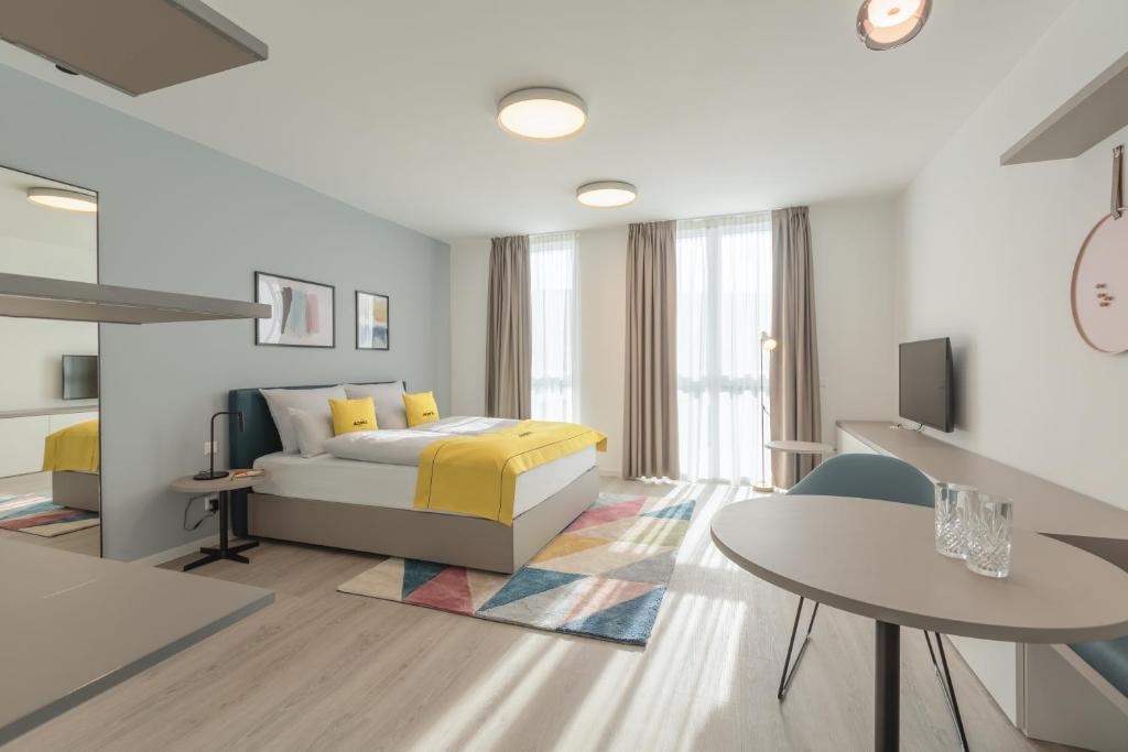 acora Heidelberg Living the City - Apartments في هايدلبرغ: غرفة نوم بيضاء مع سرير وطاولة