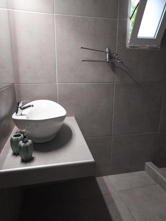 La salle de bains est pourvue d'un lavabo blanc et d'une douche. dans l'établissement Michael&Marika's Traditional House, à Limenaria