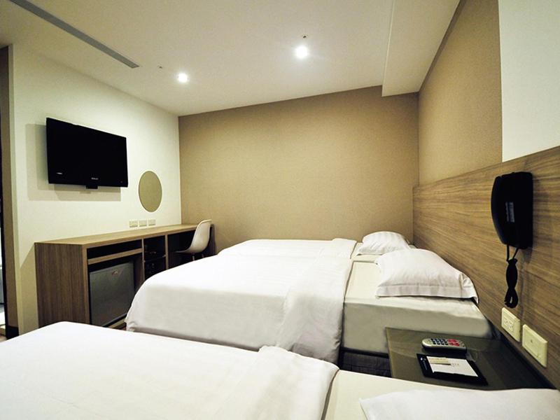 a hotel room with two beds and a flat screen tv at The Riverside Hotel International in Kaohsiung