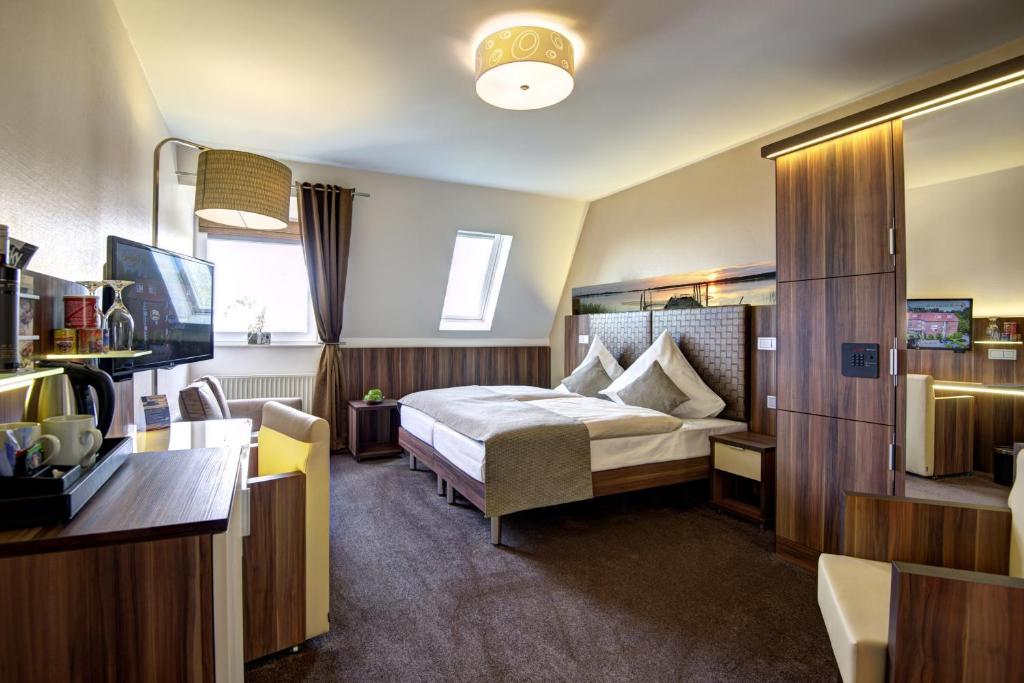 バート・ツヴィッシェンアーンにあるHotel Am Badeparkのベッドとデスクが備わるホテルルームです。
