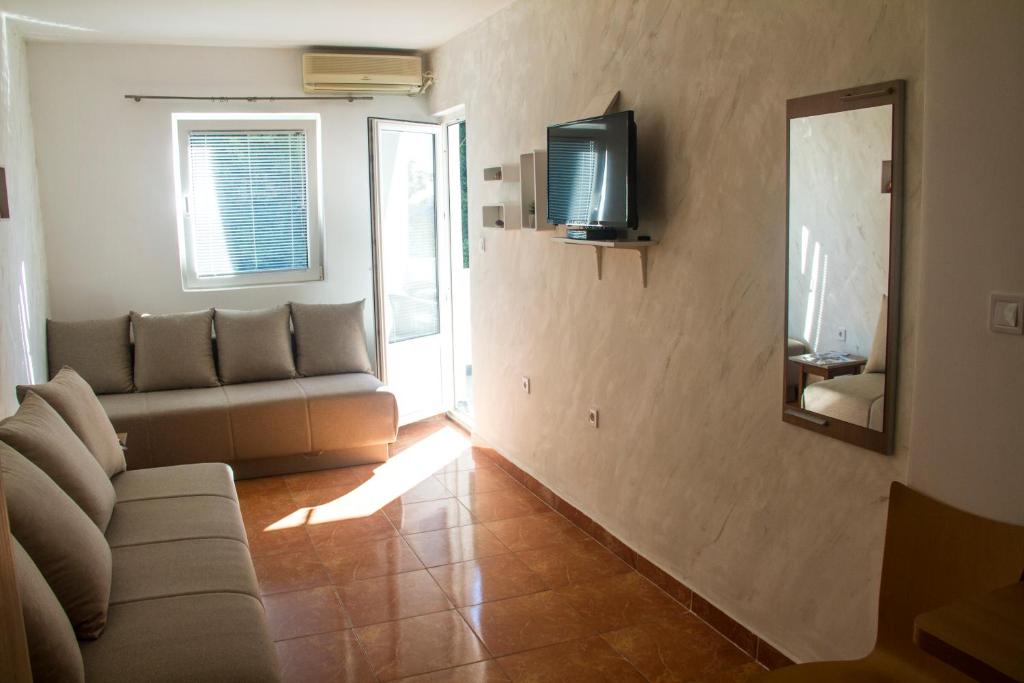 a living room with a couch and a television on a wall at Apartment San Stefan in Sveti Stefan