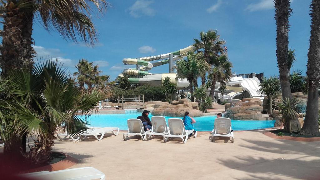 three people sitting in chairs in front of a water park at La Perle du Littoral in Vias